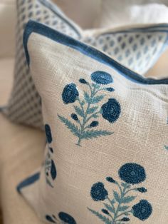 two blue and white pillows sitting on top of a couch