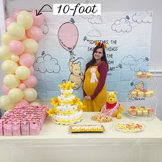 a woman standing in front of a table with desserts and balloons on the wall