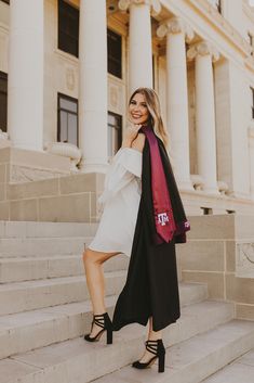 a woman standing on the steps in front of a building wearing a coat and heels