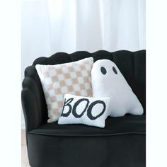 a black chair with two pillows on it and a ghost pillow next to it that says boo