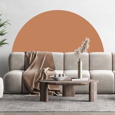 a living room with a couch, coffee table and potted plant in front of an orange circle