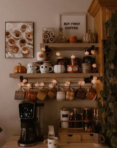 there are coffee cups on the shelf above the coffee maker and other items in the kitchen