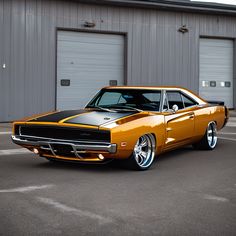 an orange and black muscle car parked in front of two garage doors on a parking lot