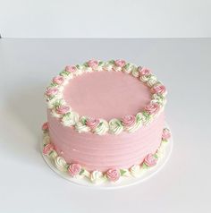 a pink and white cake with roses on it