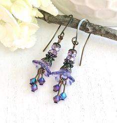 These dreamy hand-painted lightweight drop earrings have translucent lilac-hued lucite flowers with delicate Swarovski crystals, Czech glass beads, and antique brass plated spacers I've given the flowers a wash of magical multi-hued translucent color that will evoke a magical fairy garden. At first glance they seem a lovely shade of lilac, but when the light hits, an array of gorgeous colors appear giving them a subtle stained glass effect. They hang from long elegant antique brass earring wires Magical Fairy Garden, Lilac Fairy, Lucite Flower Earrings, Stained Glass Effect, Glass Effect, Magical Fairy, Earring Wires, Brass Earrings, Czech Glass Beads