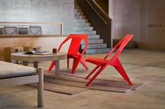 two red chairs sitting on top of a rug next to a table with a phone