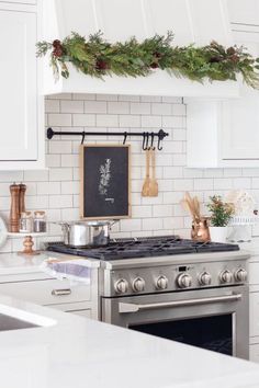 a stove top oven sitting inside of a kitchen next to a christmas wreath on the wall