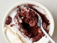 a white bowl filled with ice cream and brownie crumbs next to a spoon