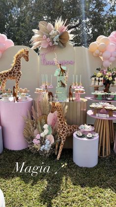 a dessert table with giraffes, balloons and other decorations on top of it