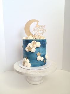 a blue and white birthday cake with stars, moon and clouds on the top tier