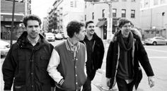 black and white photograph of four men walking down the street