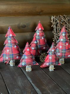 three red plaid christmas trees sitting on top of a wooden table