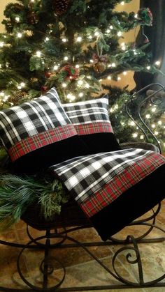 a christmas tree with lights in the background and plaid pillows on a sleigh