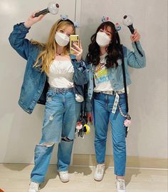 two young women wearing face masks and holding up cell phones in front of their faces