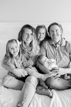 black and white photograph of family sitting on bed