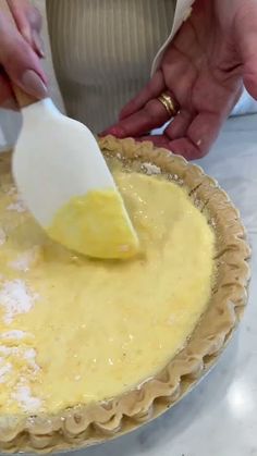 a person using a spatula to mix batter into a pie crust