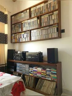 a room with a bed, bookshelf and stereo system