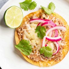 a taco topped with meat, onions and cilantro on a white plate