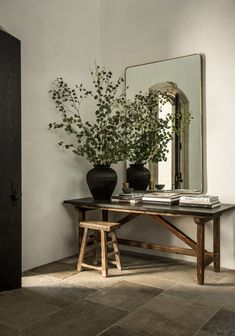 a table with two vases sitting on top of it next to a mirror and door