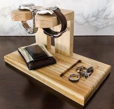 a wooden stand with rings, wallet and watch on it next to a pair of handcuffs