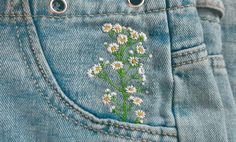 a pair of jeans with daisies embroidered on them