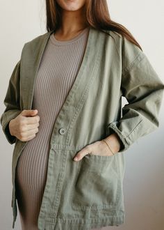 The Evergreen Jacket is a feminie canvas jacket with a relaxed fit and button front closure. This jacket is a stylish finishing peice to any outfit in a beautiful sage green color. Model is 5'8" wearing a size small Pregnant model is 5'9" in 3rd trimester, wearing a size medium Olive Cotton Outerwear For Fall, Olive Cotton Utility Jacket For Fall, Solid Color Utility Jacket For Everyday Fall Wear, Olive Long Sleeve Cotton Utility Jacket, Green Cotton Button-up Outerwear, Everyday Khaki Long Sleeve Outerwear, Olive Cotton Button-up Outerwear, Olive Button-up Cotton Outerwear, Olive Cotton Outerwear With Button Closure