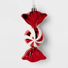 a red glass ornament with a white ribbon hanging from it's side