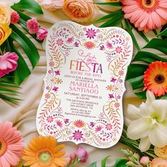 the wedding card is surrounded by flowers and greenery, including an assortment of different colors