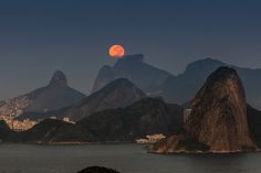 a full moon is seen over the mountains in rio