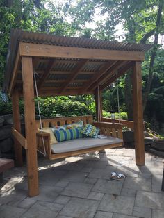 a wooden swing bed sitting on top of a stone patio