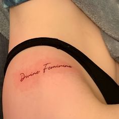 a woman's back with the word divine feminine written on her left side ribcage