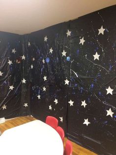 a room with black and white stars on the wall, red chairs and a table