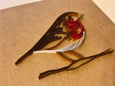 a bird made out of paper sitting on top of a piece of cardboard with scissors