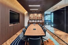 a conference room with wooden tables and chairs in front of a flat screen tv mounted on the wall