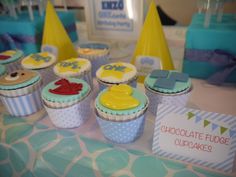 some cupcakes are sitting on a table with blue and yellow frosted decorations