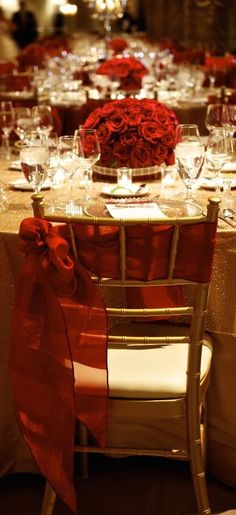 the table is set with red roses and wine glasses for an elegant wedding reception or special event