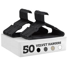 a pair of black velvet hangers sitting on top of a white box with five different colors