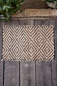 a black and white rug sitting on top of a wooden floor next to a potted plant