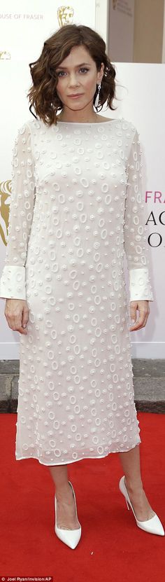 a woman standing on top of a red carpet next to a white dress and heels