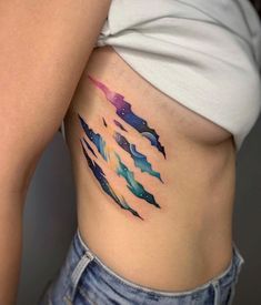 a woman's stomach with colorful watercolor tattoos on her belly and bottom part