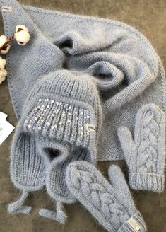 a knitted hat, mittens and gloves are laying on the ground