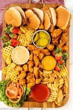 a platter filled with chicken, fries and coleslaw on top of a checkered table cloth