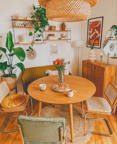 a wooden table surrounded by chairs and potted plants