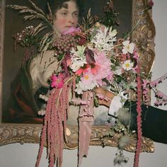 a woman holding a bouquet of flowers in front of a painting