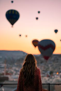 a woman looking at hot air balloons in the sky