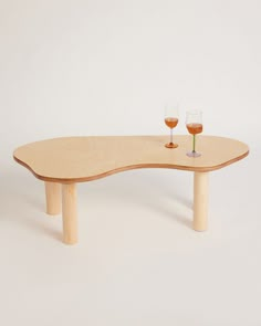 a wooden table with two wine glasses on it and a white wall in the background