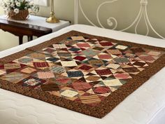 a bed with a quilt on top of it in a room next to a table