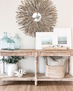 a wooden table topped with vases and pictures next to a wall mounted sunburst