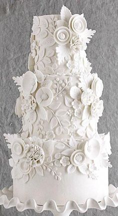 a three tiered white wedding cake decorated with flowers