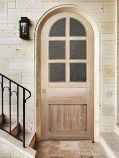 a wooden door sitting on the side of a white brick wall next to a set of stairs